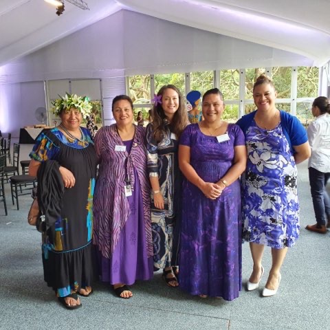 Five beautiful women in bright purple attire gathered for a photo at the event