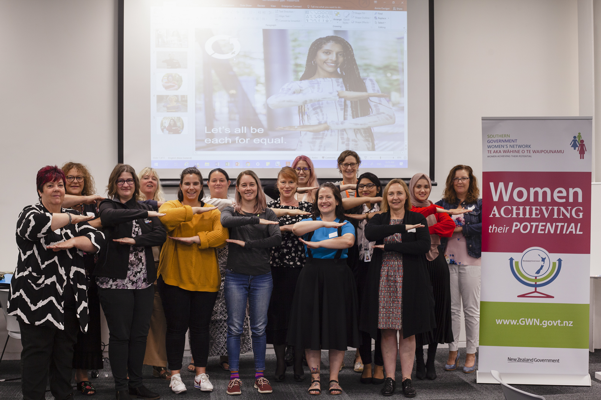 SGWN IWD breakfast attendees demonstrate the Each for Equal symbol