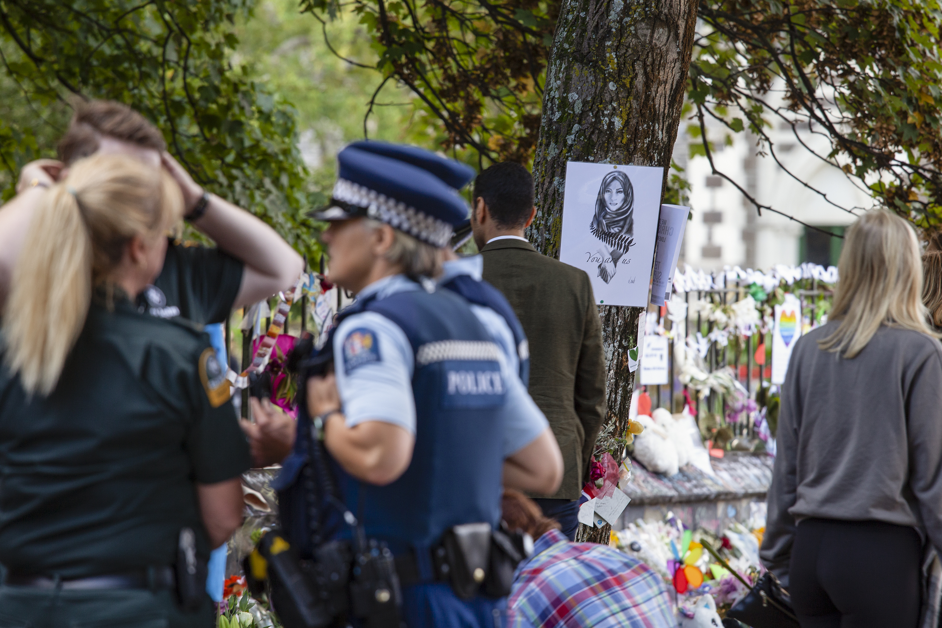 Memorial site: police presence, community supporters, a drawing of a Muslim woman reads 'You are us'