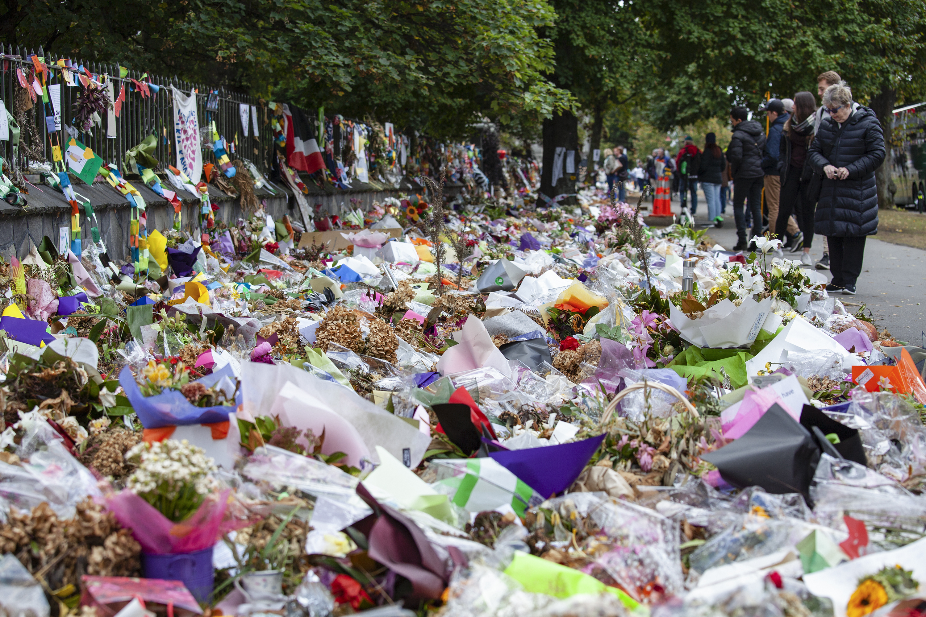 A sea of flowers, cards, banners and gifts floods the walkway in front of one of the mosques as people gather to view and read 